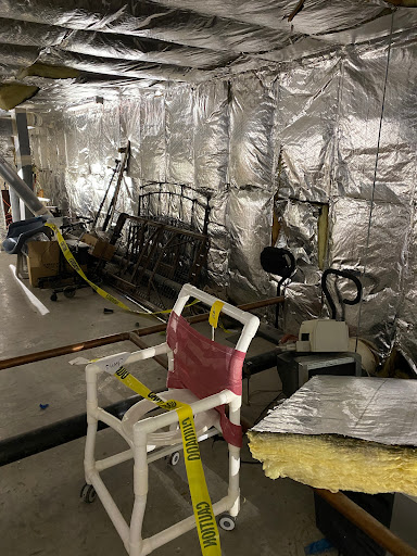 An interior space undergoing renovation, featuring silver insulation and various construction tools.