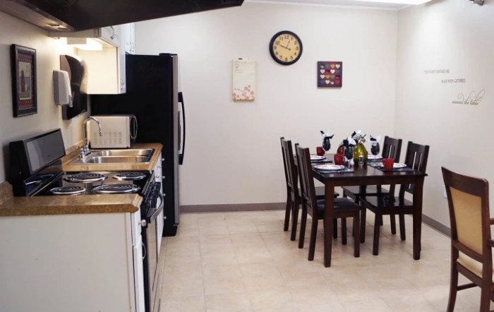A modern kitchen with a dining area, featuring a table set with chairs and various appliances.