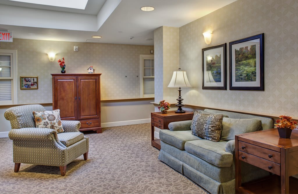 A cozy living room with a sofa, armchair, and wooden furniture.