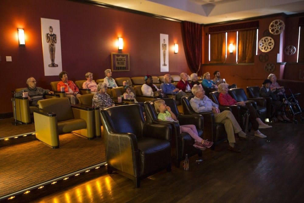 A group of people seated in a small movie theater, attentively watching a film.