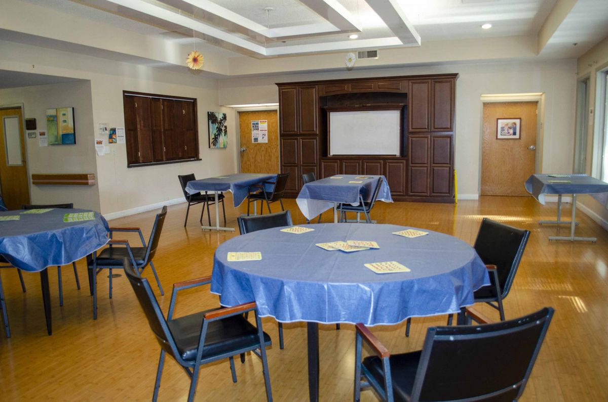 A well-equipped meeting room with round tables and chairs, featuring a projector screen.