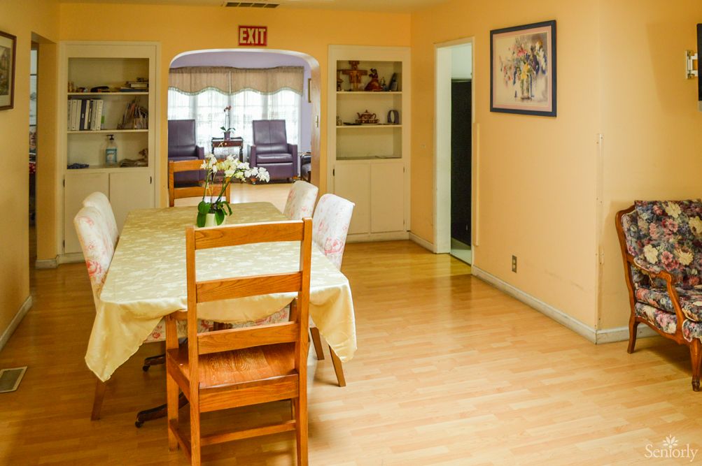 A cozy dining area with a wooden table and chairs, adorned with a flower vase.