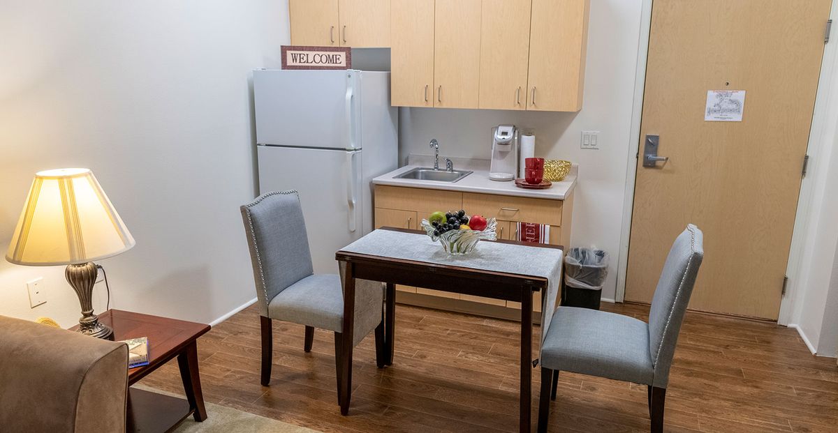 A small kitchen and dining area with a table, two chairs, and a refrigerator.