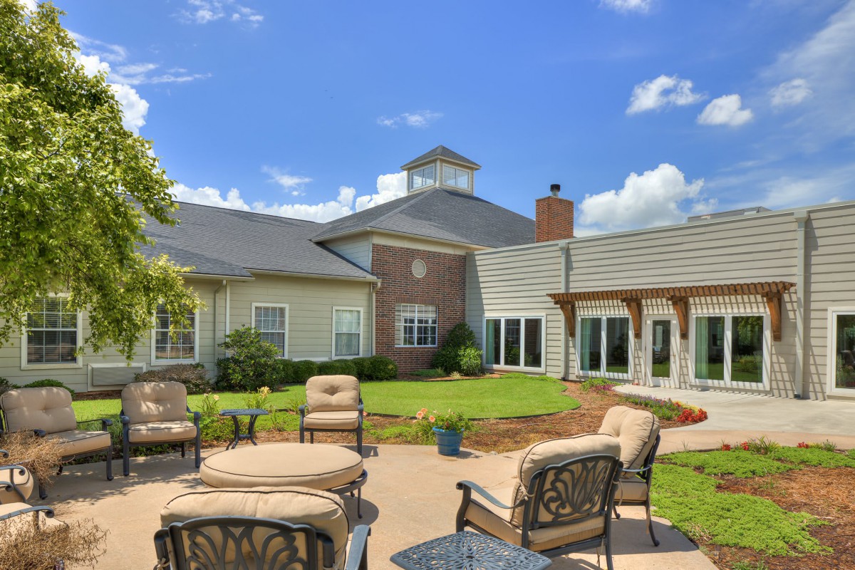A sunny outdoor patio area with comfortable seating and a landscaped garden.