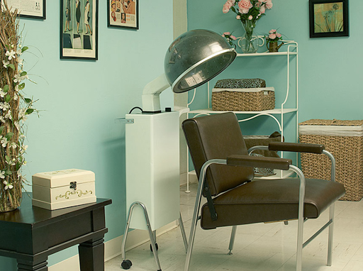 A vintage-style hair salon setup featuring a classic hairdryer and comfortable seating.