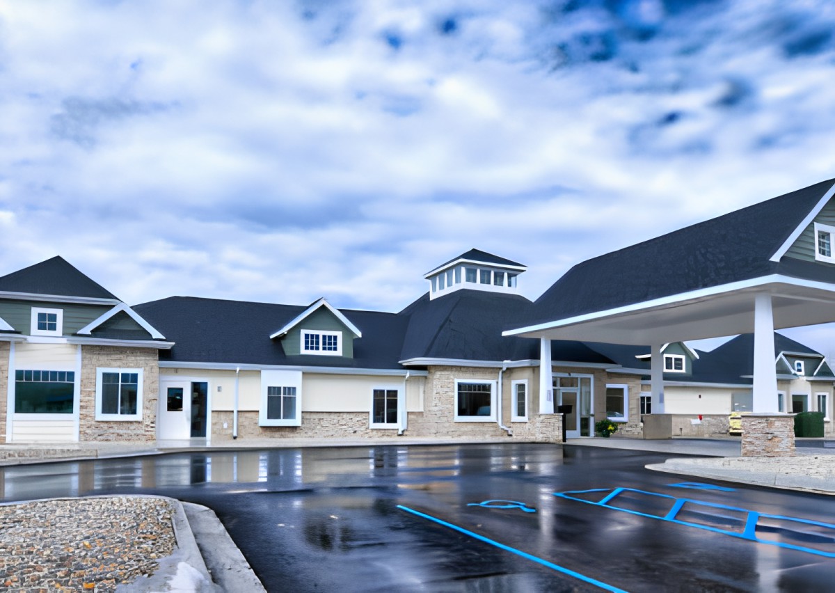 A modern building with a pitched roof and large windows under a cloudy sky.