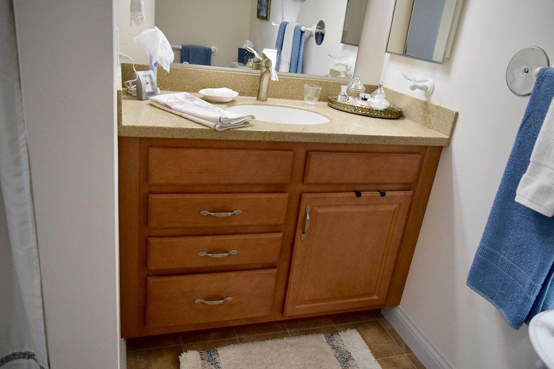 A bathroom vanity with a sink, mirror, and wooden cabinet.