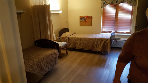 A simple and cozy room featuring two beds and minimal furniture, illuminated by natural light.
