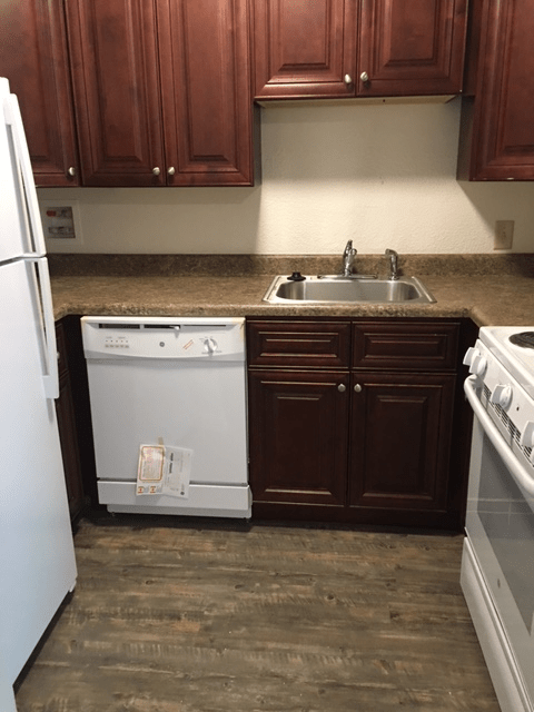 A compact kitchen with wooden cabinets and essential appliances.