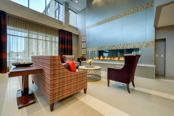 A modern living room with a high ceiling, featuring a stylish fireplace and contemporary furniture.