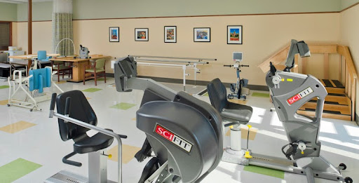 A well-equipped fitness center featuring various exercise machines and framed photographs on the walls.