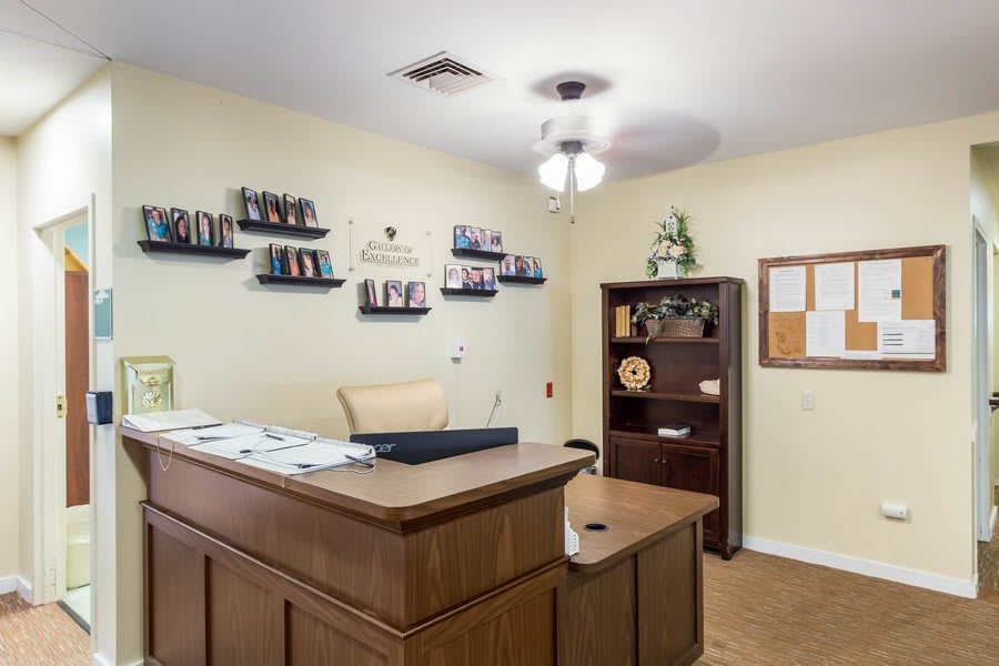 A tidy office reception area with wooden desk and bookshelves.