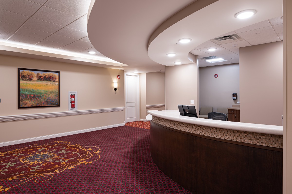 A hotel reception area with a curved desk and carpeted floors.