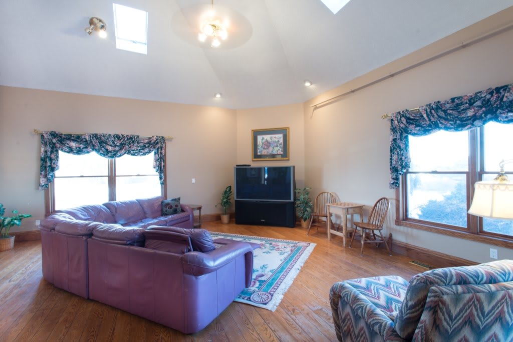 A spacious living room with a purple sofa, wooden flooring, and a large television.