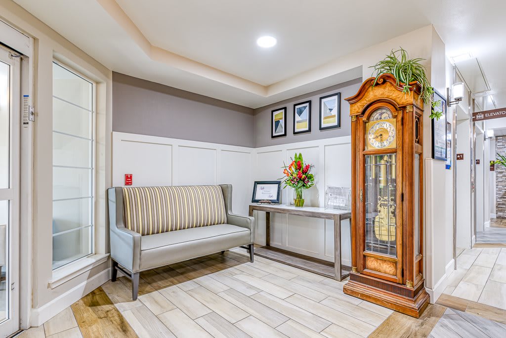 A modern living room interior featuring a bench, grandfather clock, and decorative artwork.