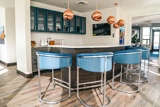 A stylish modern kitchen bar featuring sleek blue chairs and elegant copper pendant lights.