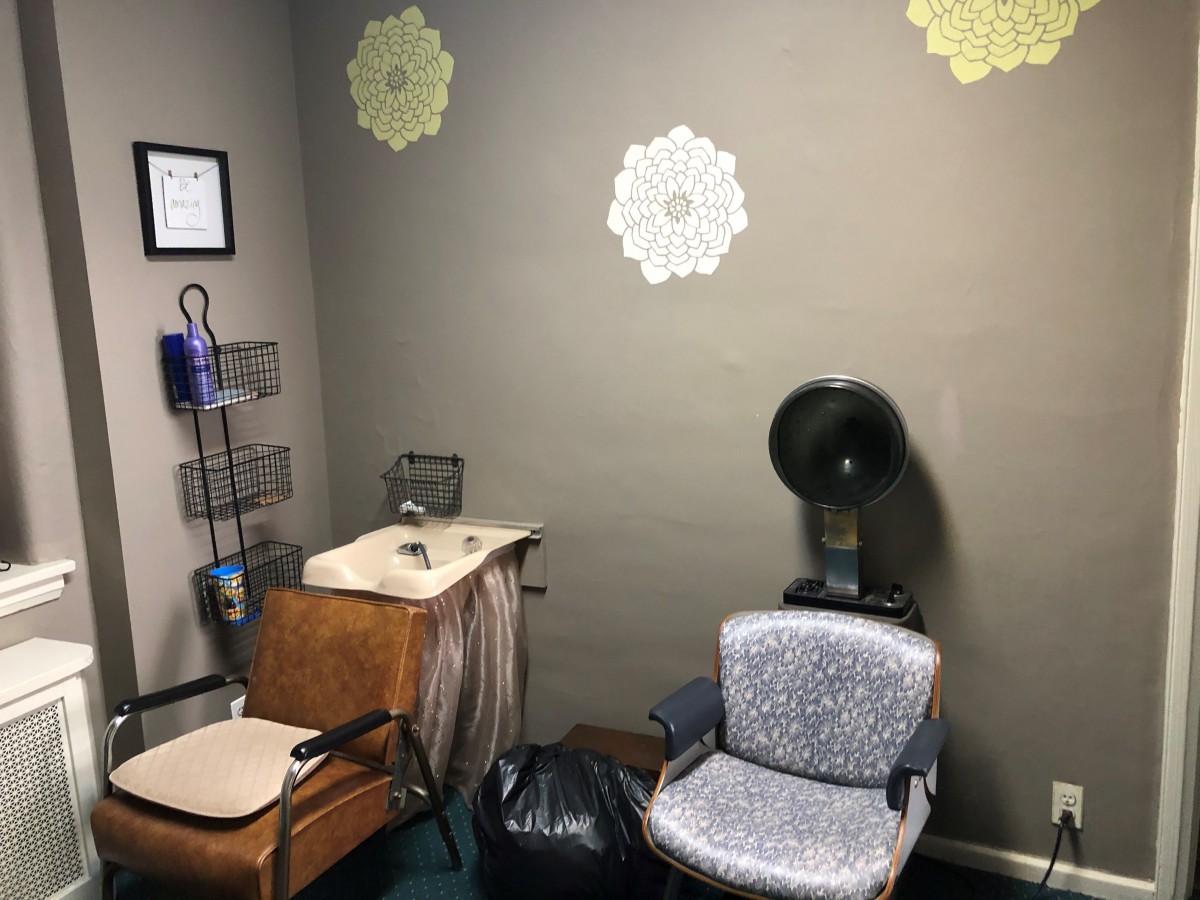 A cozy vintage-style hair salon corner with a dryer chair and decorative wall accents.