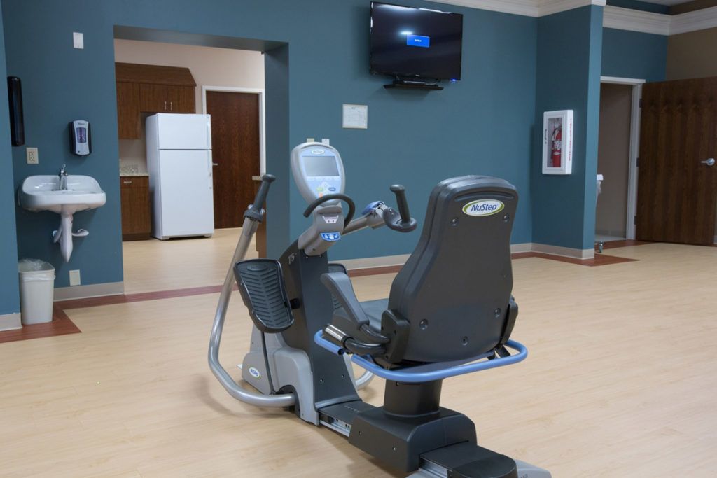 A modern gym with an exercise bike and a wall-mounted television in a spacious, empty room.