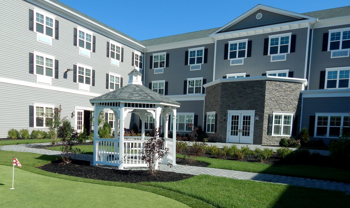 A well-maintained residential building with a white gazebo and lush green lawn.