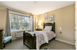 A cozy bedroom with a single bed, large window, and soft lighting.