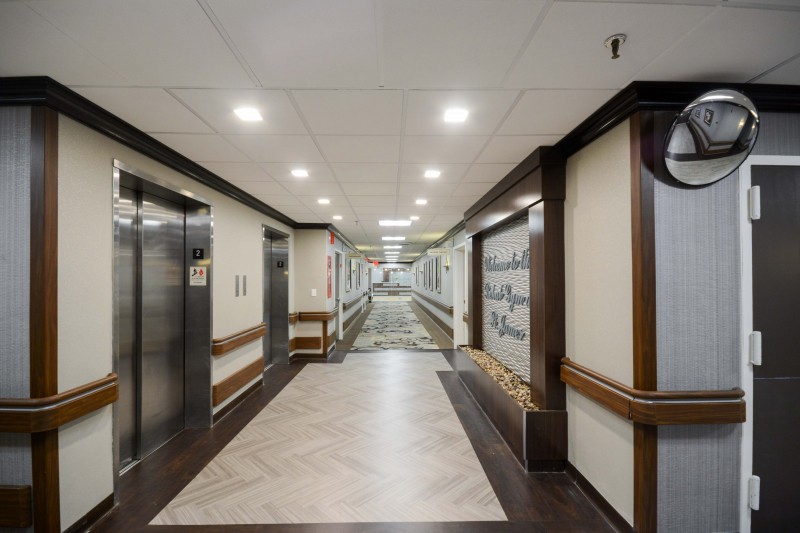A modern hospital corridor with elevators and bright lighting.