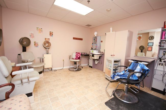 A cozy and well-equipped salon interior featuring hairdressing chairs, mirrors, and beauty equipment.