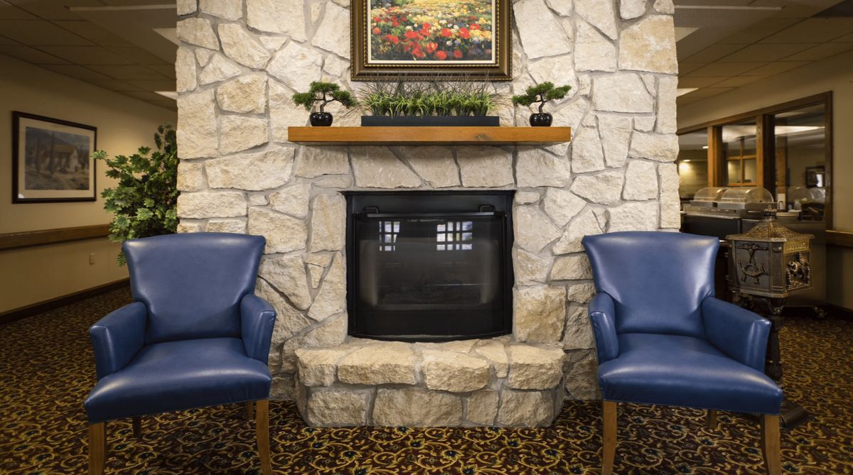 A cozy living room setup featuring a stone fireplace, blue chairs, and decorative accents.