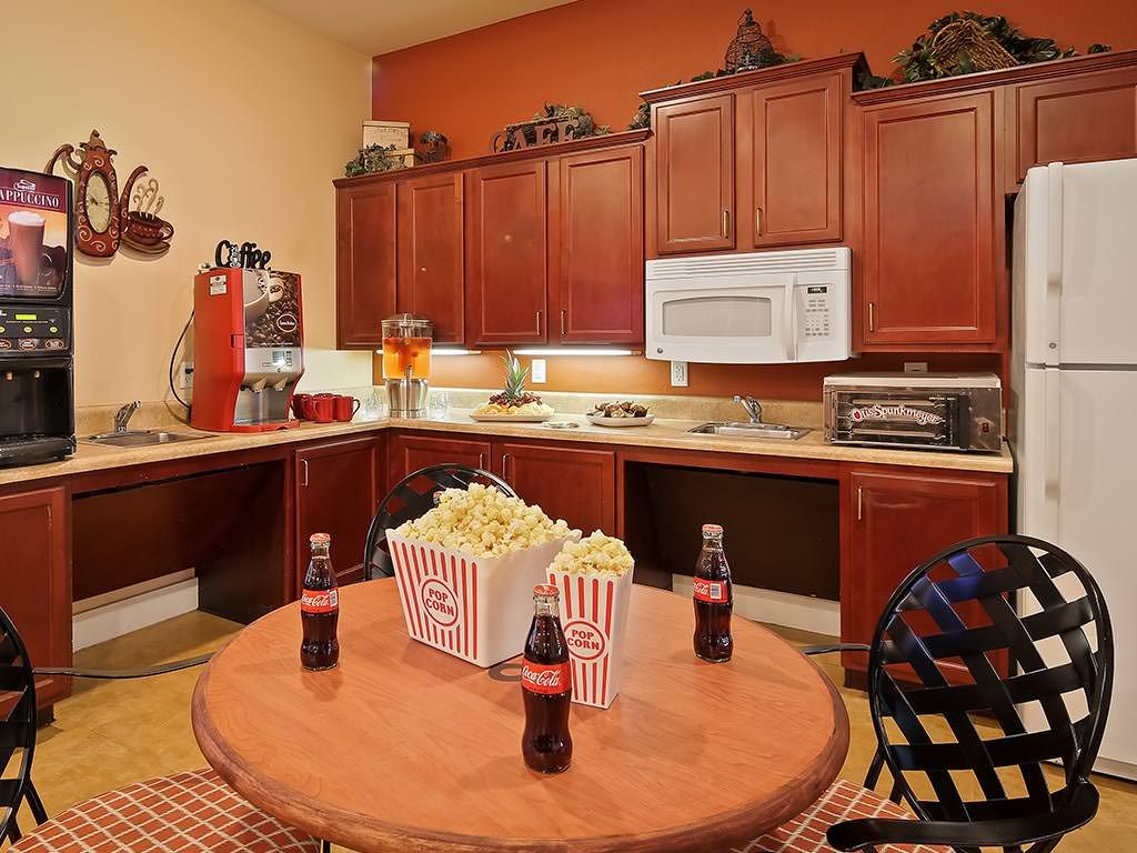 A cozy kitchen setup with a table featuring popcorn and soda bottles, surrounded by wooden cabinets and modern appliances.