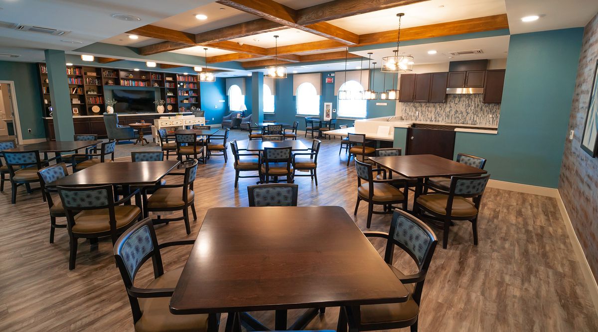 A spacious dining area with neatly arranged tables and chairs, featuring warm lighting and modern decor.