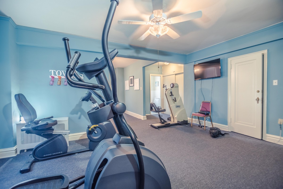 A home gym featuring an elliptical machine and a wall-mounted TV.