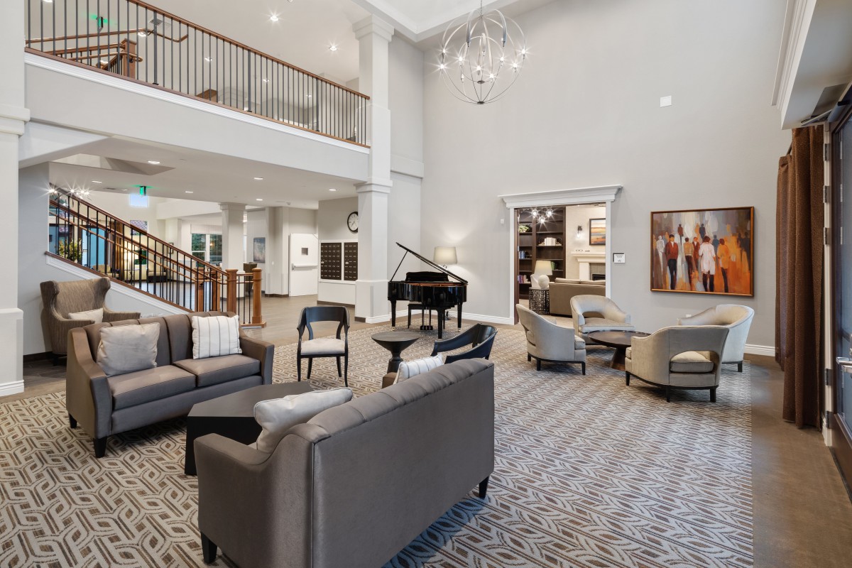 A spacious and modern lobby featuring comfortable seating, a grand piano, and elegant lighting.