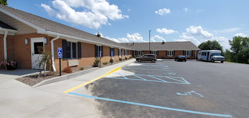 A view of a motel with a parking lot under a partly cloudy sky.
