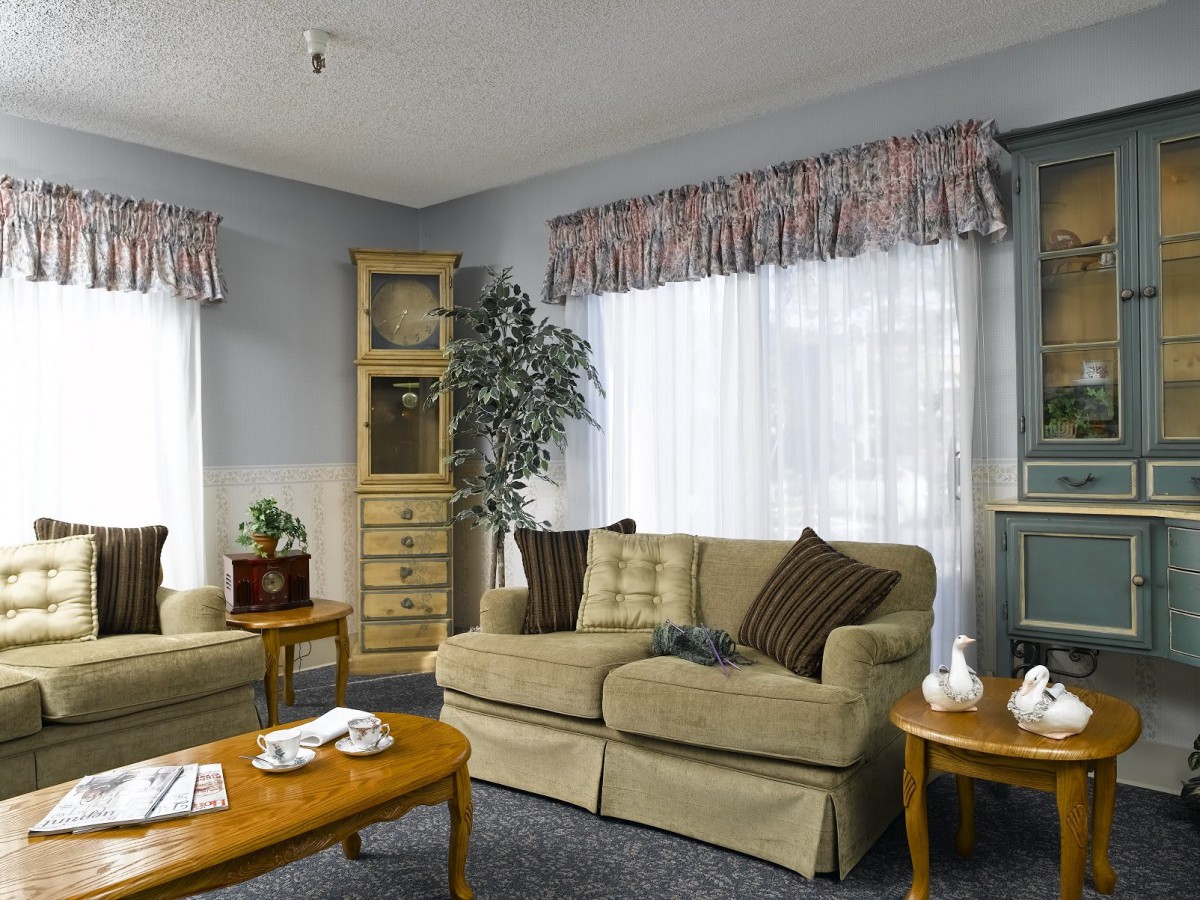 A cozy living room with beige sofas, wooden coffee tables, and decorative curtains.