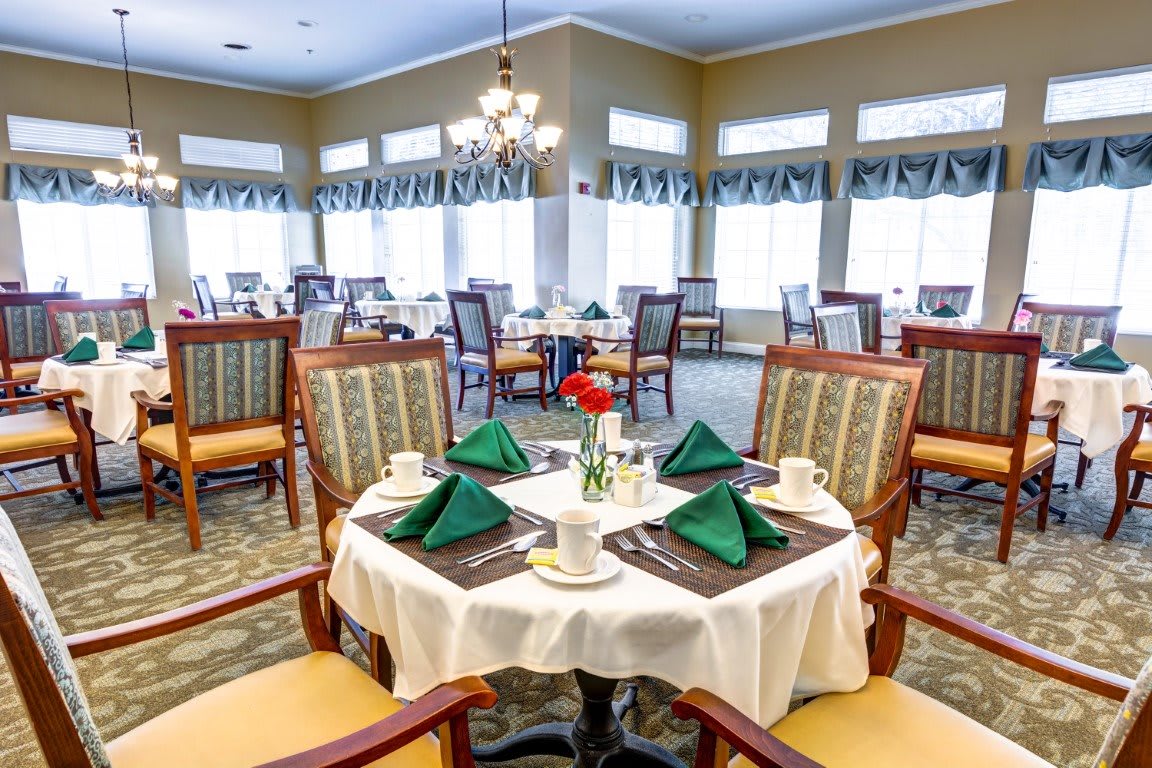 An elegantly set dining room with tables and chairs, ready for guests.