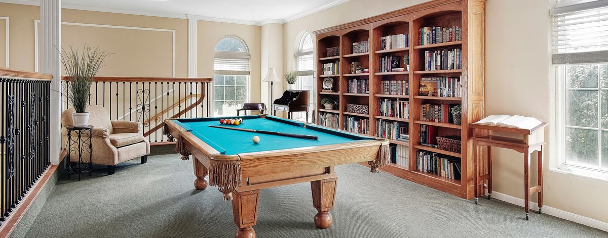 A stylish room featuring a billiards table and bookshelves, combining leisure and study.