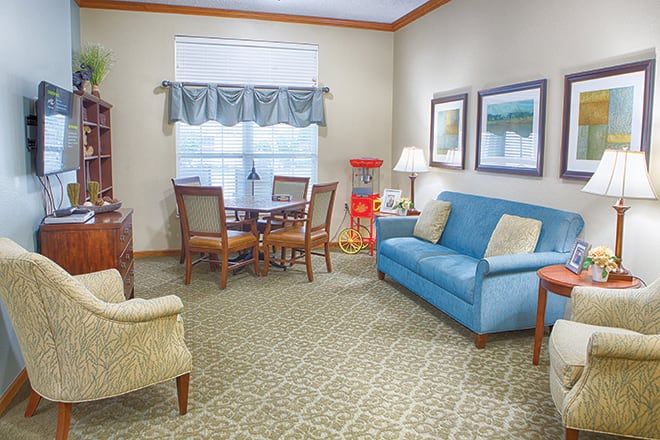 A cozy living room with a blue sofa, a dining table, and decorative elements.