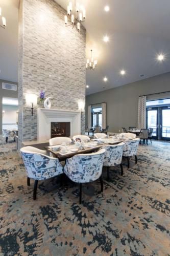 A beautifully designed dining room featuring a fireplace, elegant lighting fixtures, and stylish chairs around a large table.
