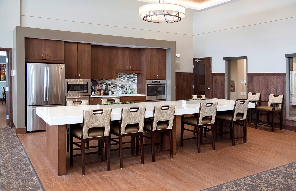A modern kitchen with a large island and seating, featuring wood cabinetry and stainless steel appliances.