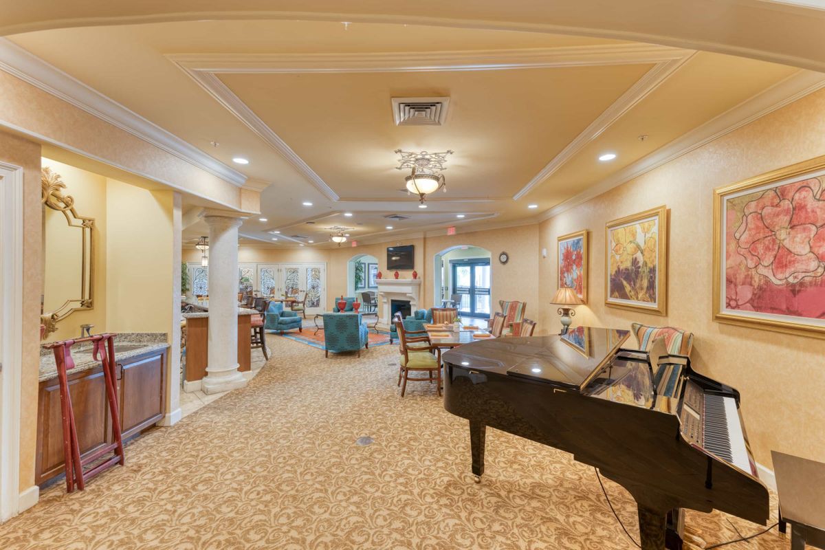 A spacious living room with a grand piano, comfortable seating, and elegant artwork.
