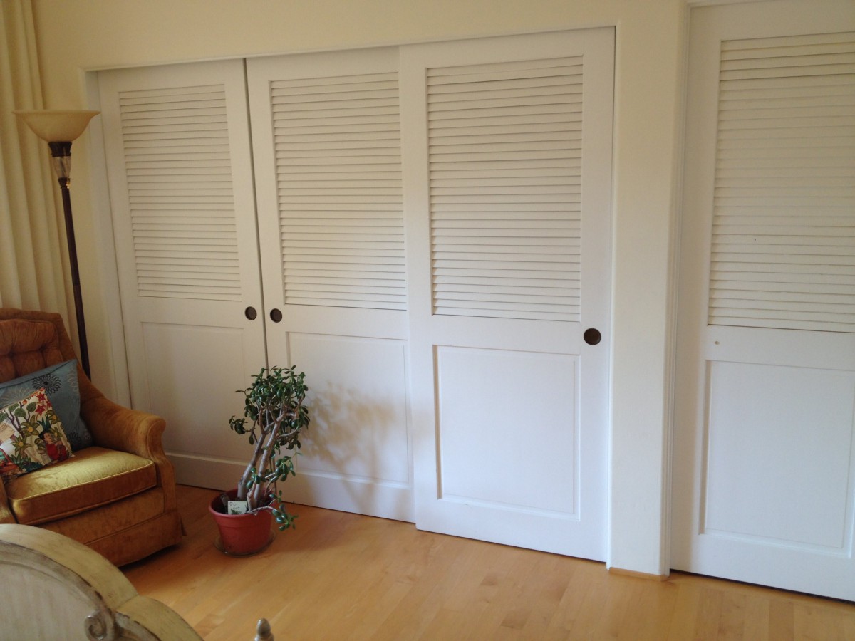 A room with louvered sliding closet doors, an indoor plant, and a chair.