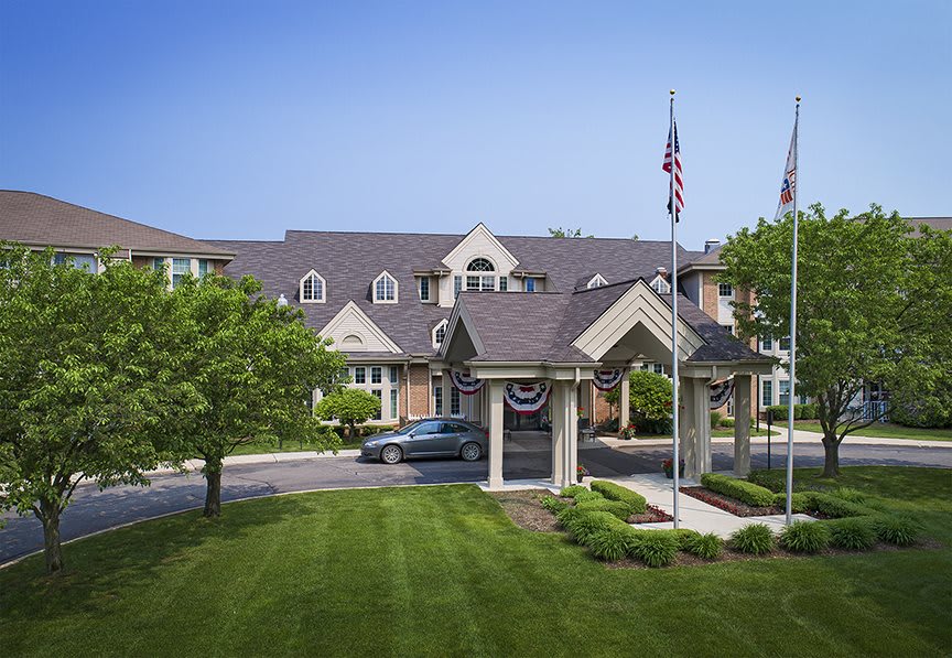 An elegant building with a well-maintained lawn and flags at the entrance.