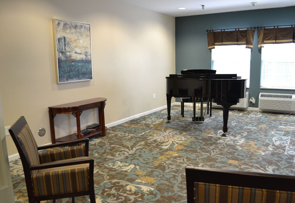 A cozy music room featuring a grand piano and seating, complemented by wall artwork.