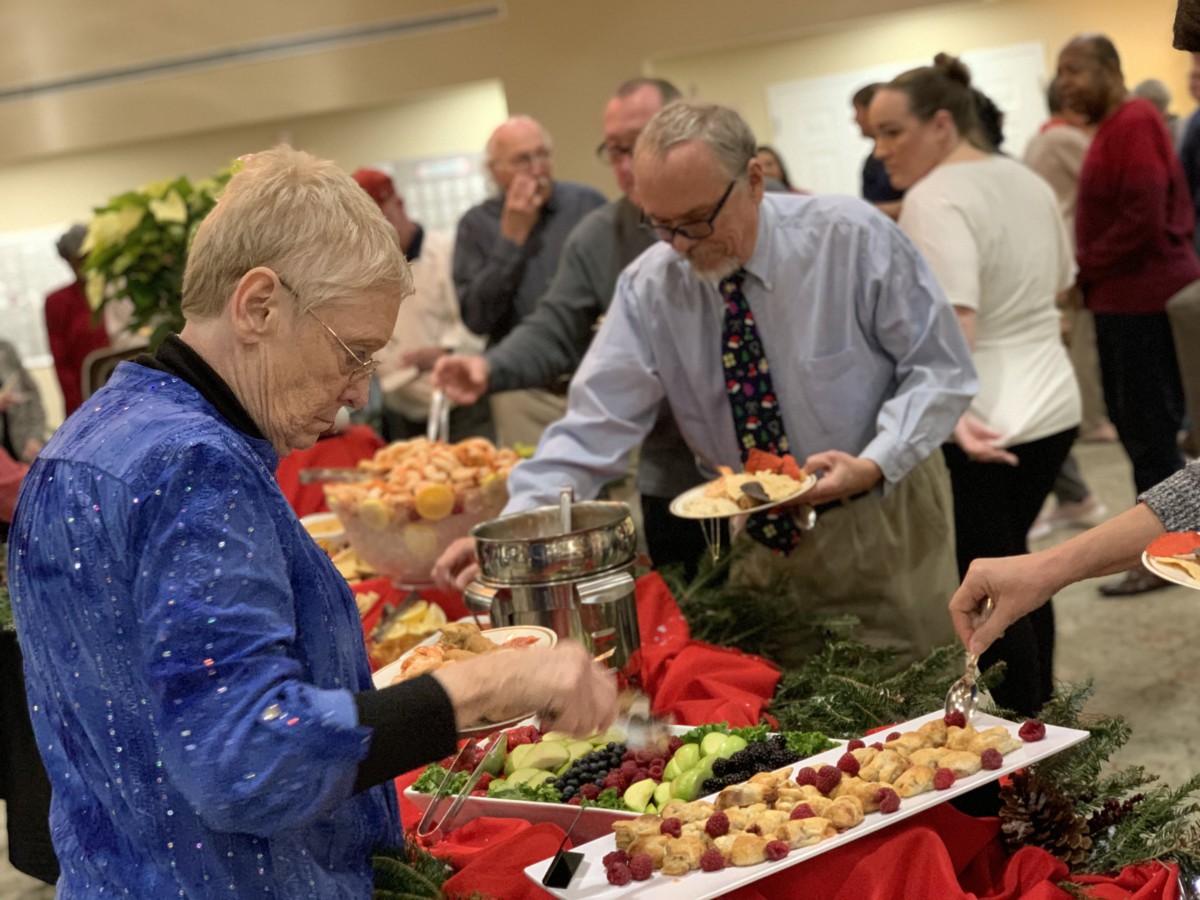People serving themselves at a buffet during a social event.