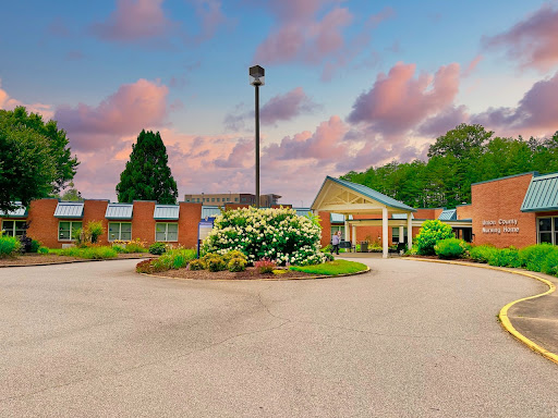 A serene view of a welcoming building surrounded by lush greenery and colorful flowers under a beautiful sky.