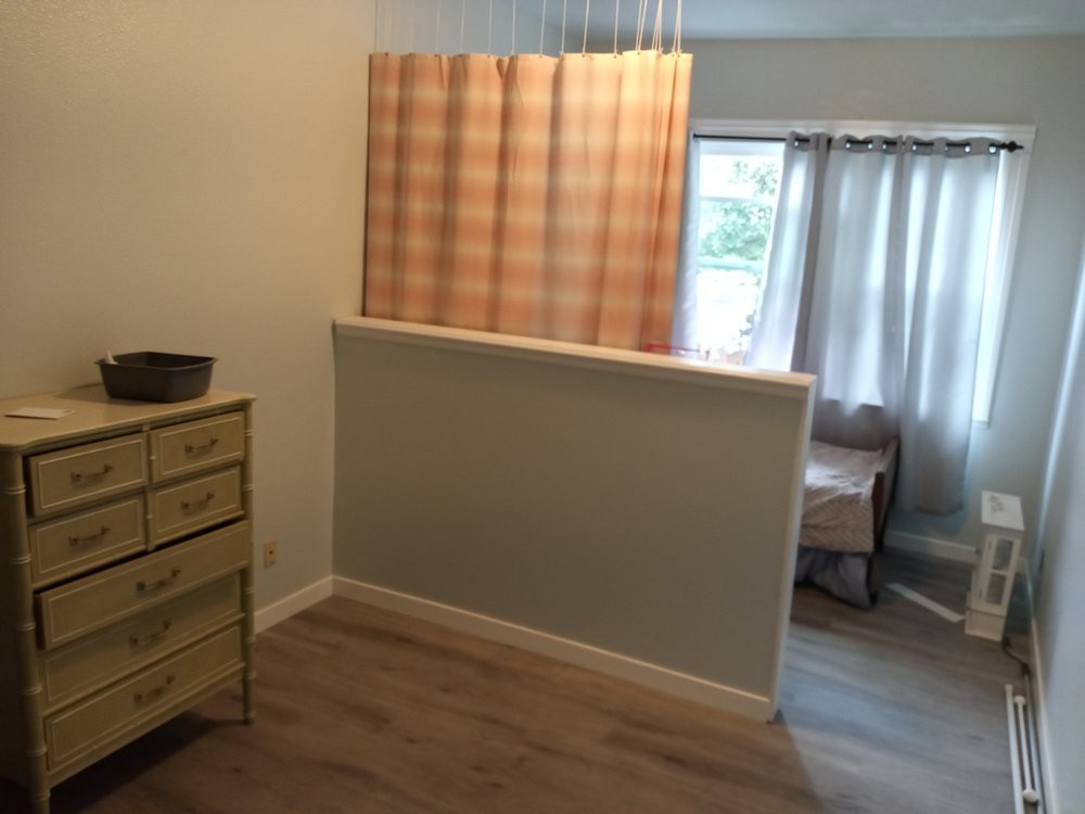 A room interior featuring a curtain, dresser, and window.