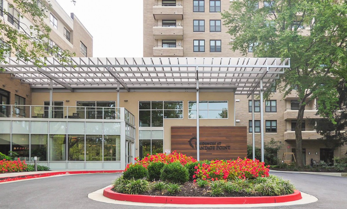 A modern building entrance with a landscaped garden and vibrant flowers.