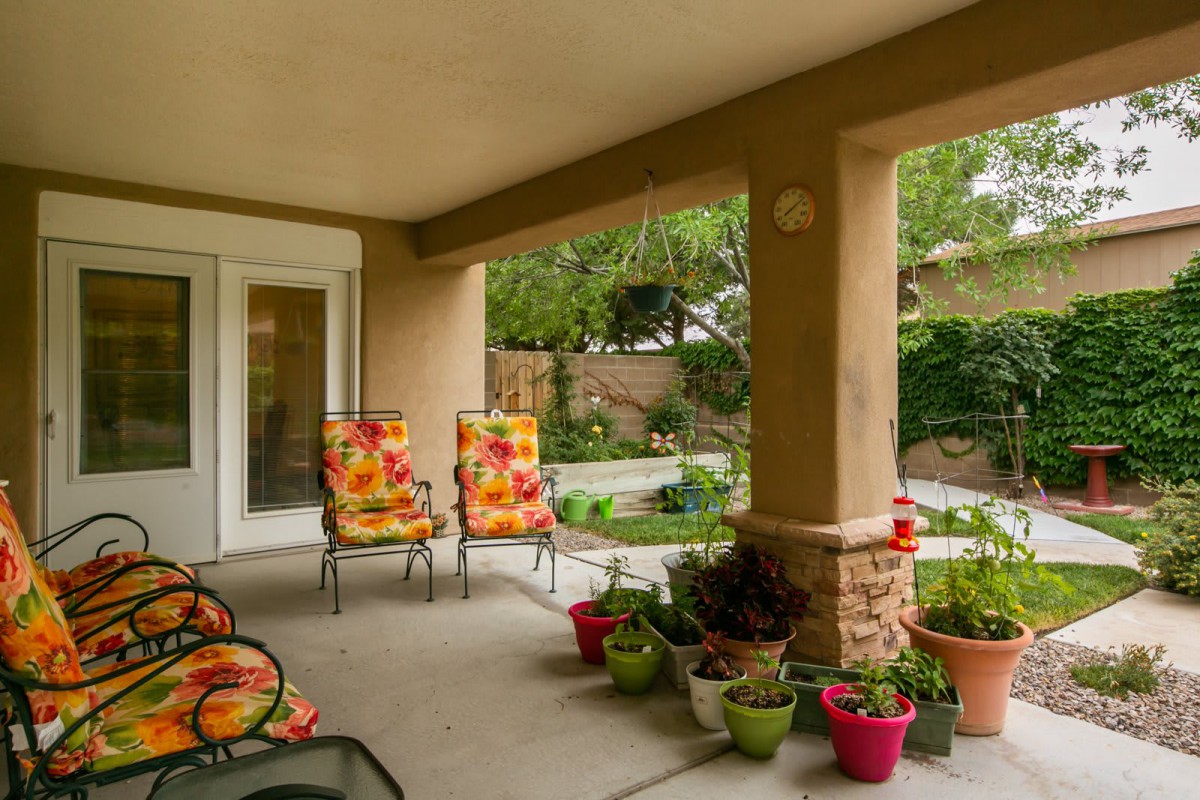 A cozy patio with colorful chairs and potted plants overlooking a well-maintained garden.
