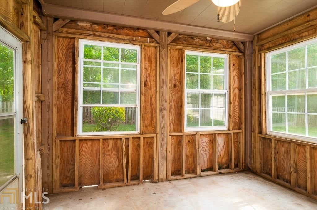 An unfinished room with exposed wood framing and two large windows.