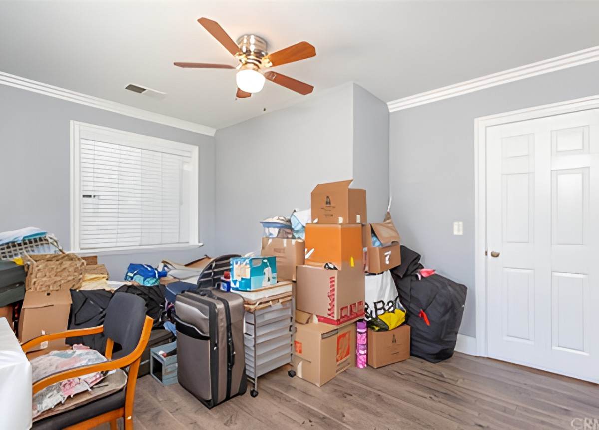 A cluttered room with stacked boxes and suitcases, indicating storage or moving.