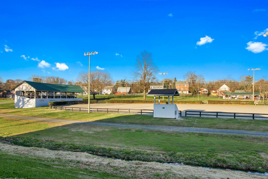 A sunny day at an outdoor baseball field with a scoreboard and surrounding trees and buildings.
